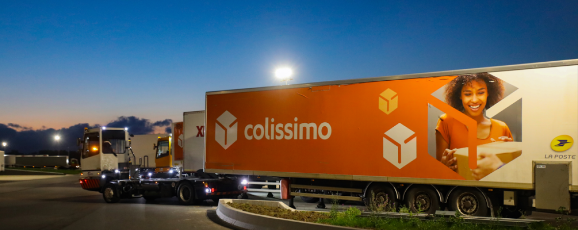 Vue extérieure de nuit d'une plateforme colis avec un camion colissimo en stationnement