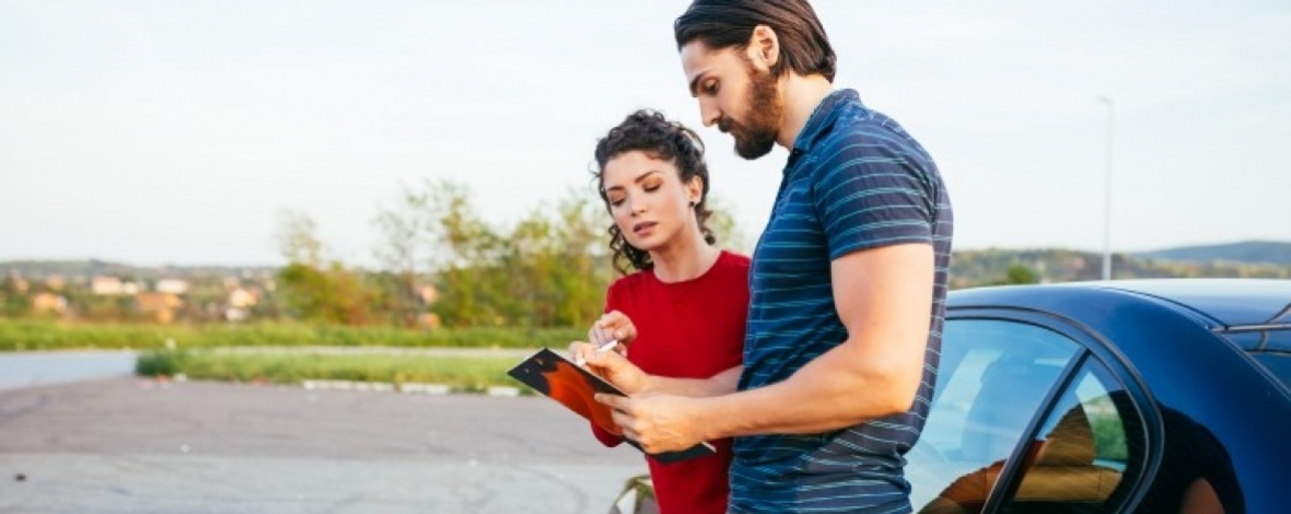 Homme et femme regardant un document devant une voiture