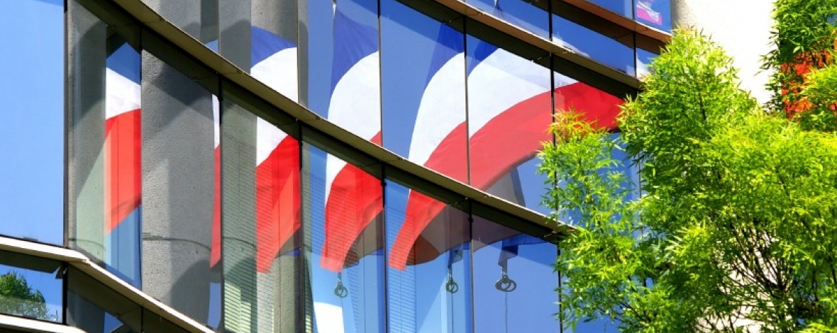 Photos de drapeaux français se reflétant dans les vitres d'un immeuble de bureaux